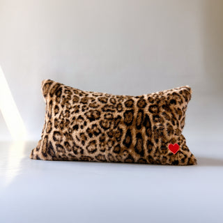 A decorative throw pillow called Muse by Loren Estes. Lumbar faux fur leopard throw pillow with sacred heart embroidered.
