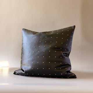 A decorative throw pillow called Relic by Loren Estes. Square 22" x 22" faux leather with gold studded pillow.